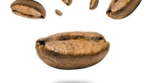 Close-up of levitating coffee beans against a white backdrop, highlighting texture.